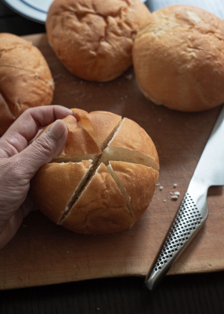 A store-bought bread roll is scored into 6 segments to create openings.