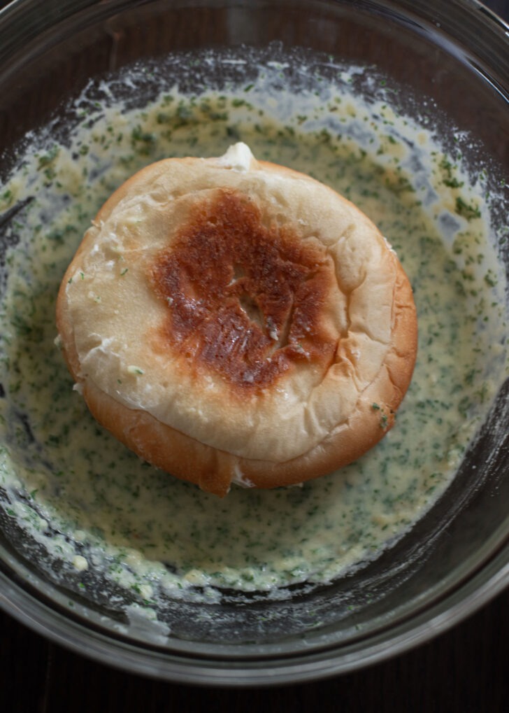 A bread roll coating with garlic butter.