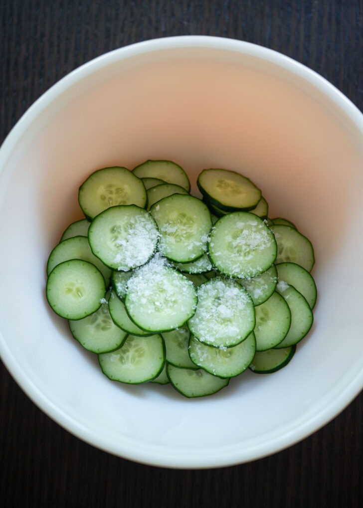 Cucumber slices coated with salt to make Korean cucumber salad.