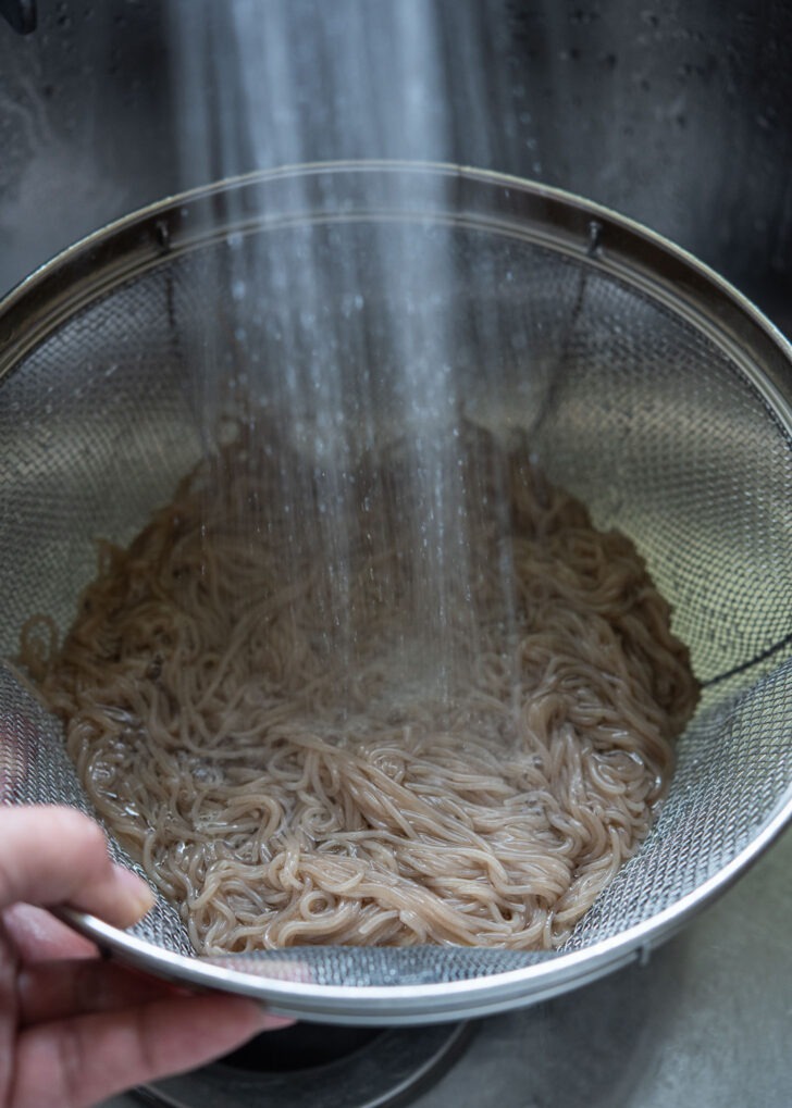 Rinsing naengmyeon noodles under the cold running water.