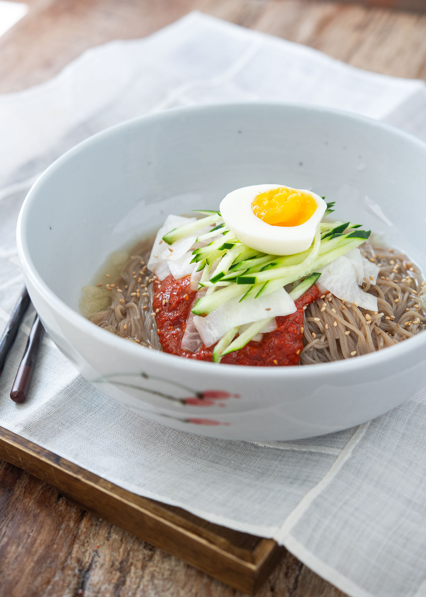 Naengmyeon, Korean cold noodles, garnished with bibim naengmyeon sauce and toppings.