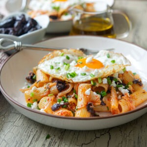 Kimchi olive pasta featuring feta cheese and fried egg as a Greek-Korean fusion dish.