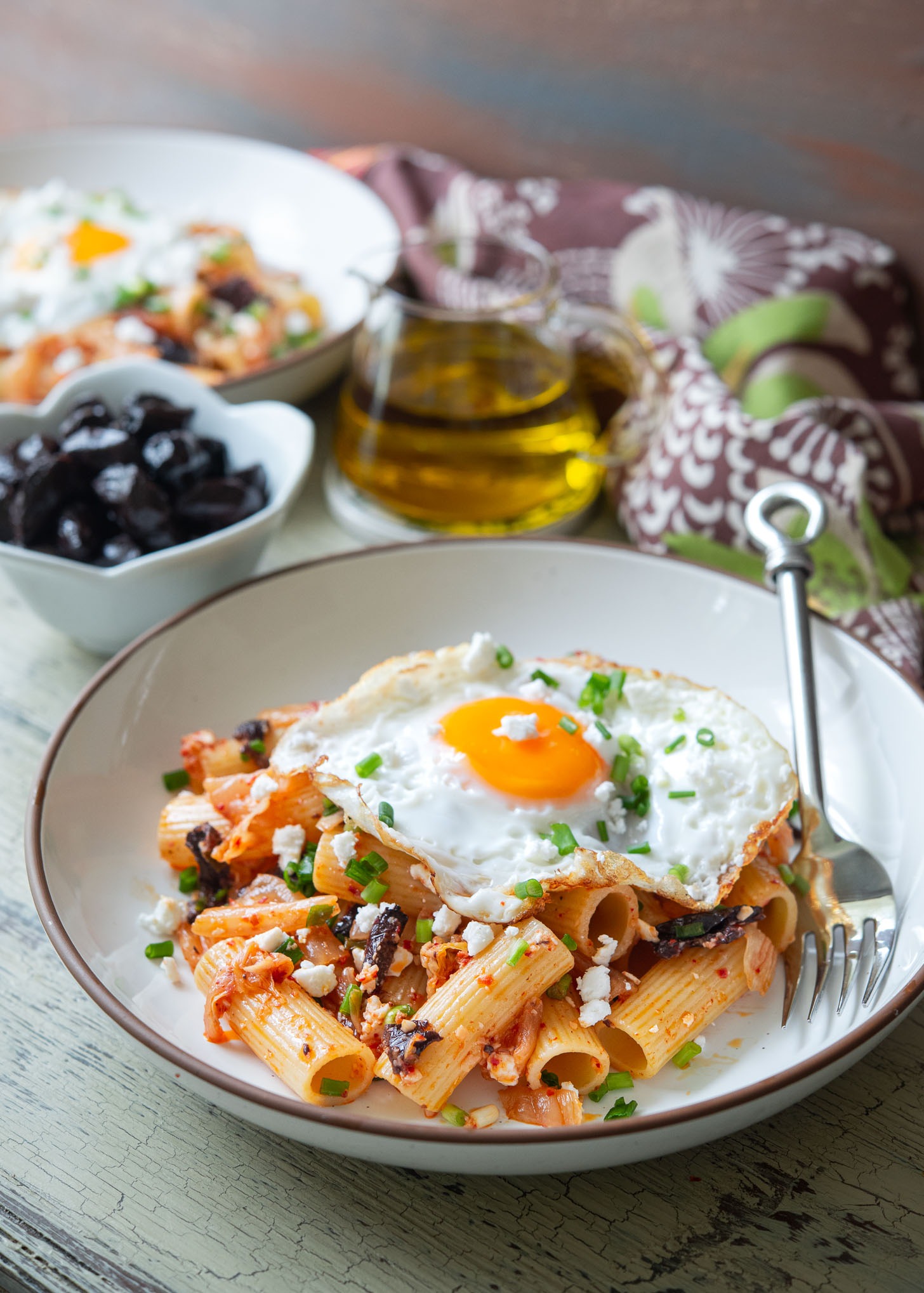 Fried egg topped over kimchi olive pasta, the Greek-Korean fusion recipe.