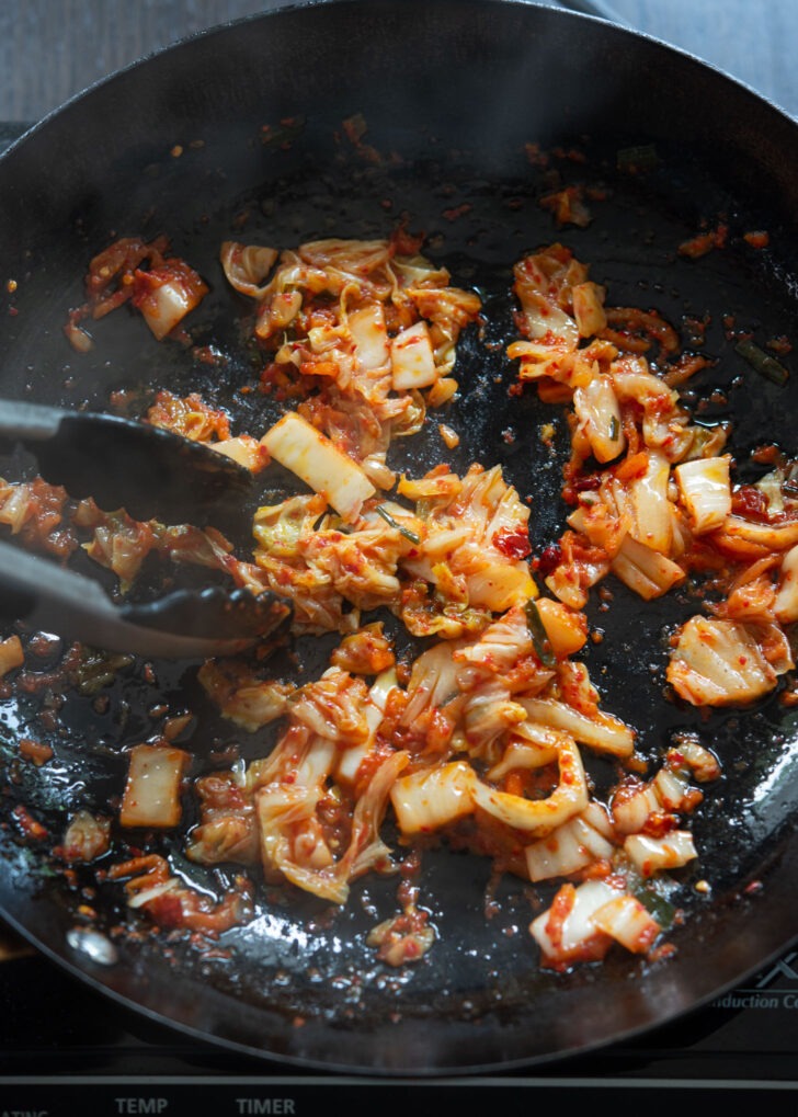 Chopped kimchi cooking in olive oil to make Mediterranean-Korean fusion pasta.