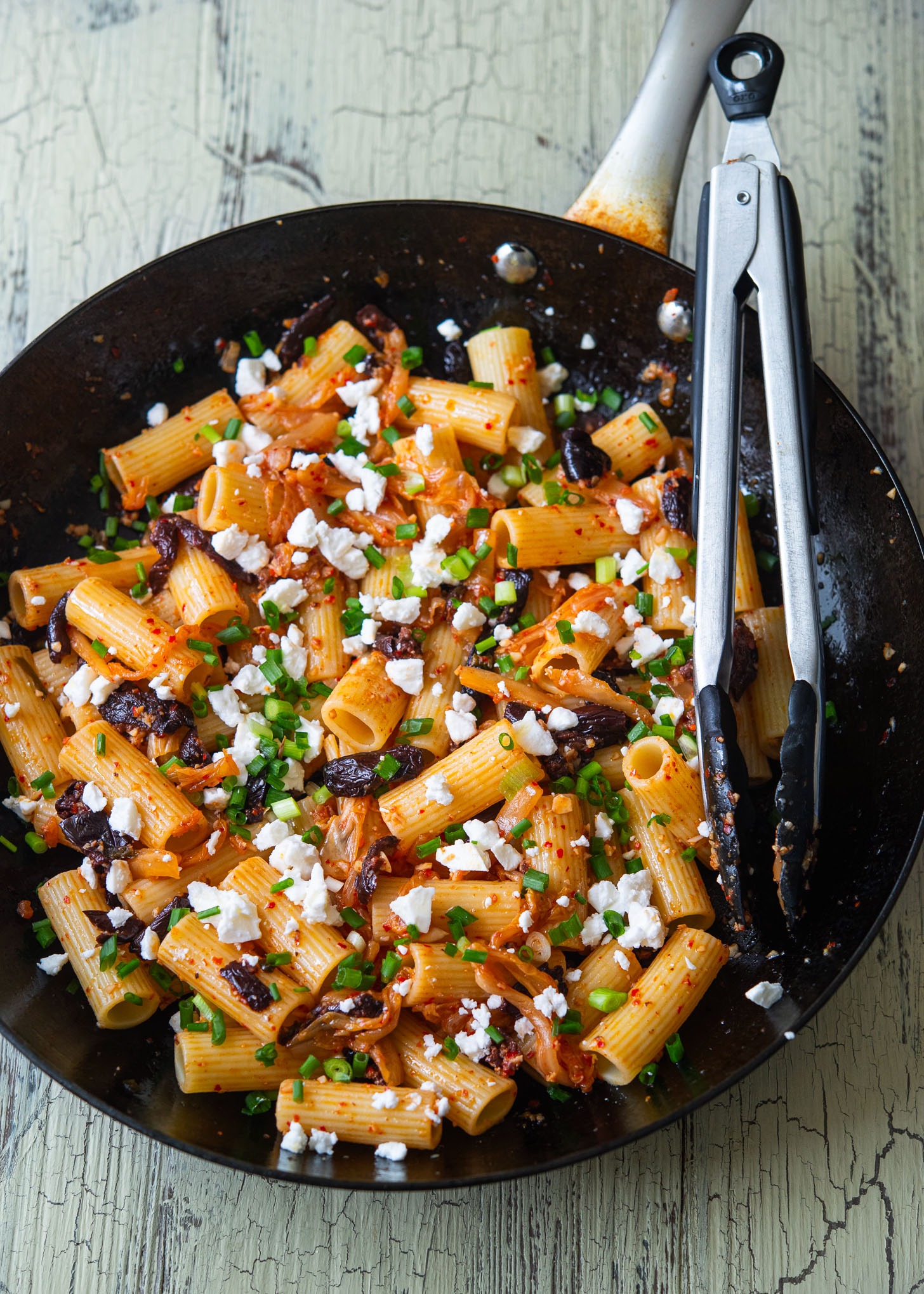 A skillet filled with kimchi olive pasta, Greek-Korean fusion style.