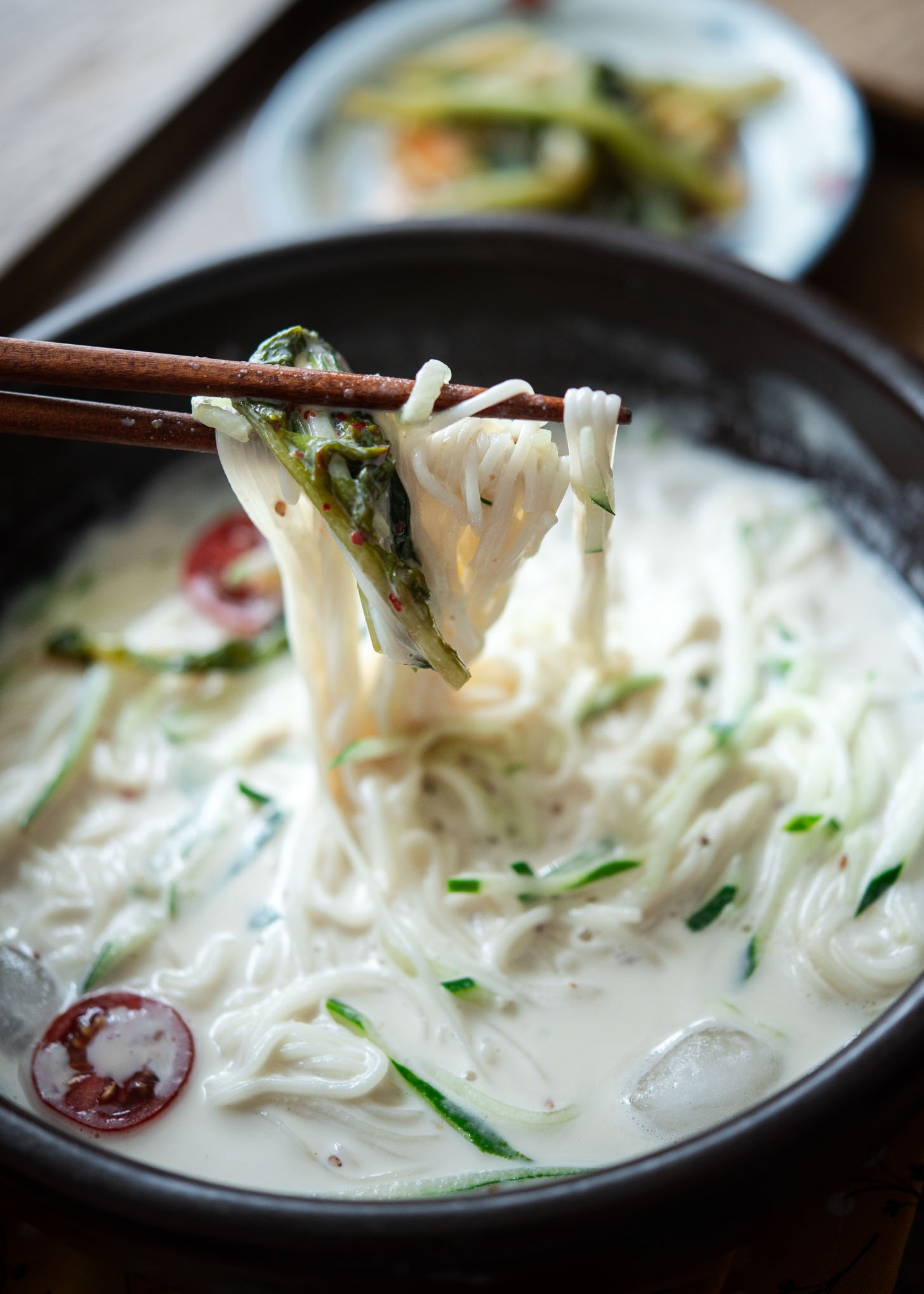 Chopsticks holding Korean summer noodles, kongguksu, from the cold soy milk soup base in a bowl