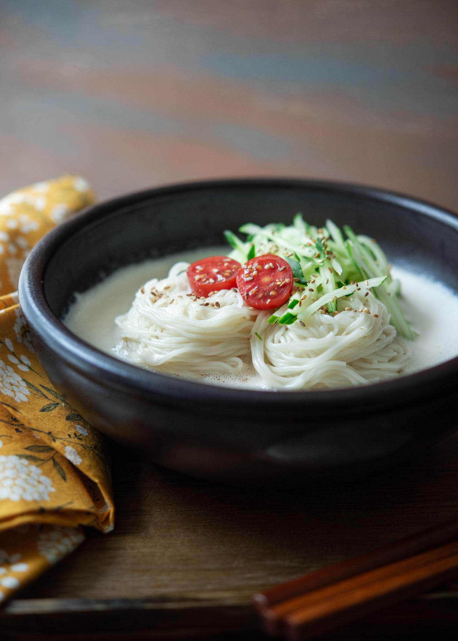 Korean cold soy milk soup noodles called kongguksu served in a bow with garnishes.