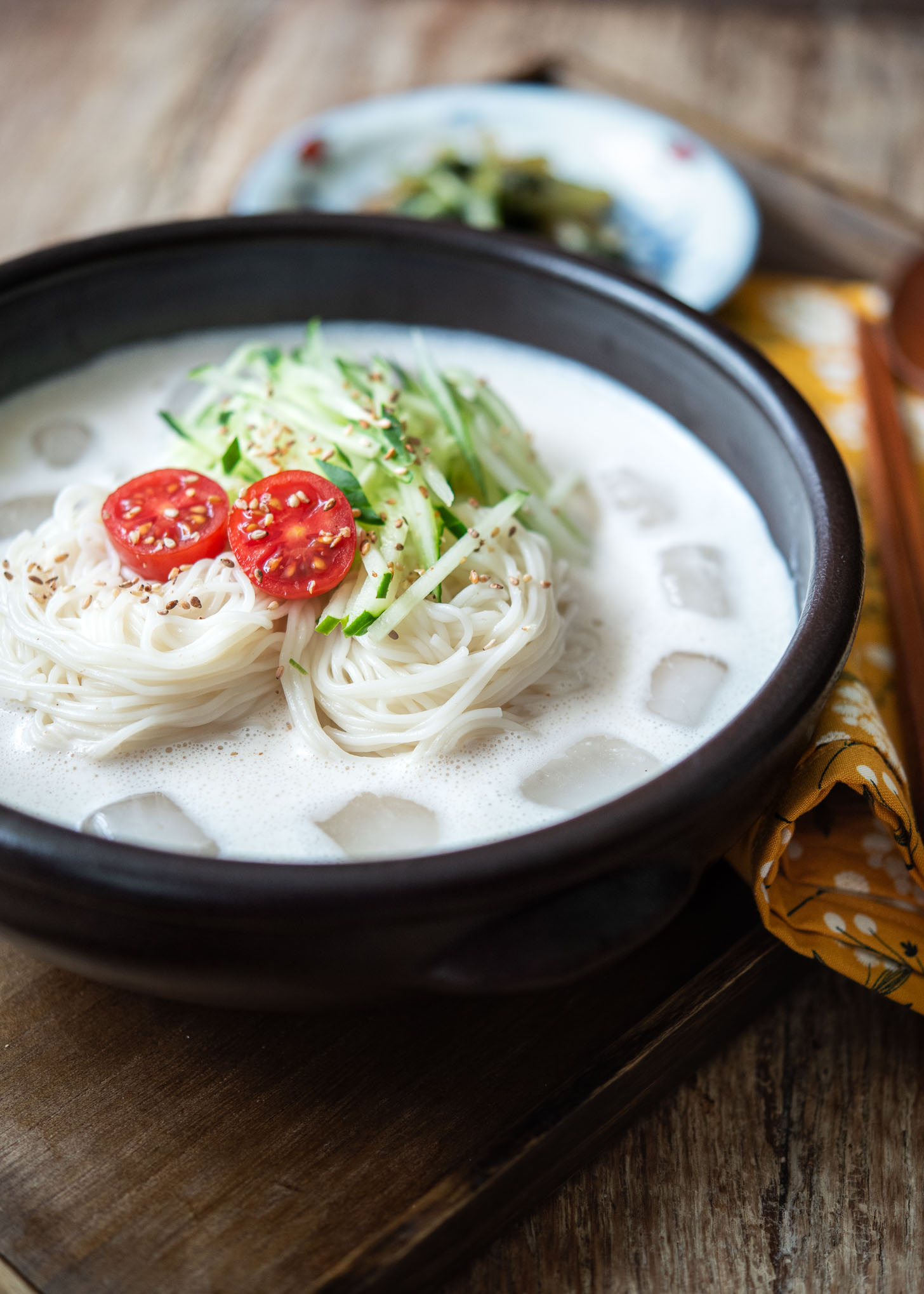 Cucumber, tomato, and ice are added to garnish kongguksu, soy milk noodle soup.