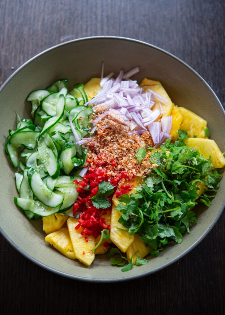 Pineapple cucumber salad ingredients combined in a bowl.
