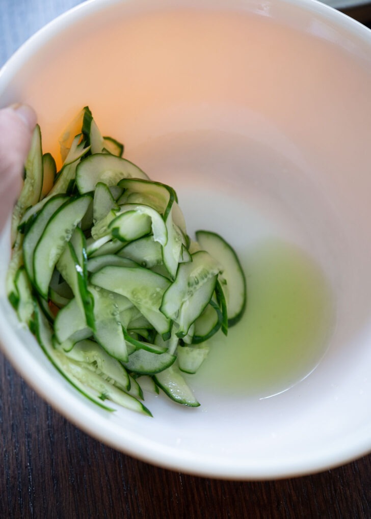 Salted cucumber releasing the moisture in a bowl.