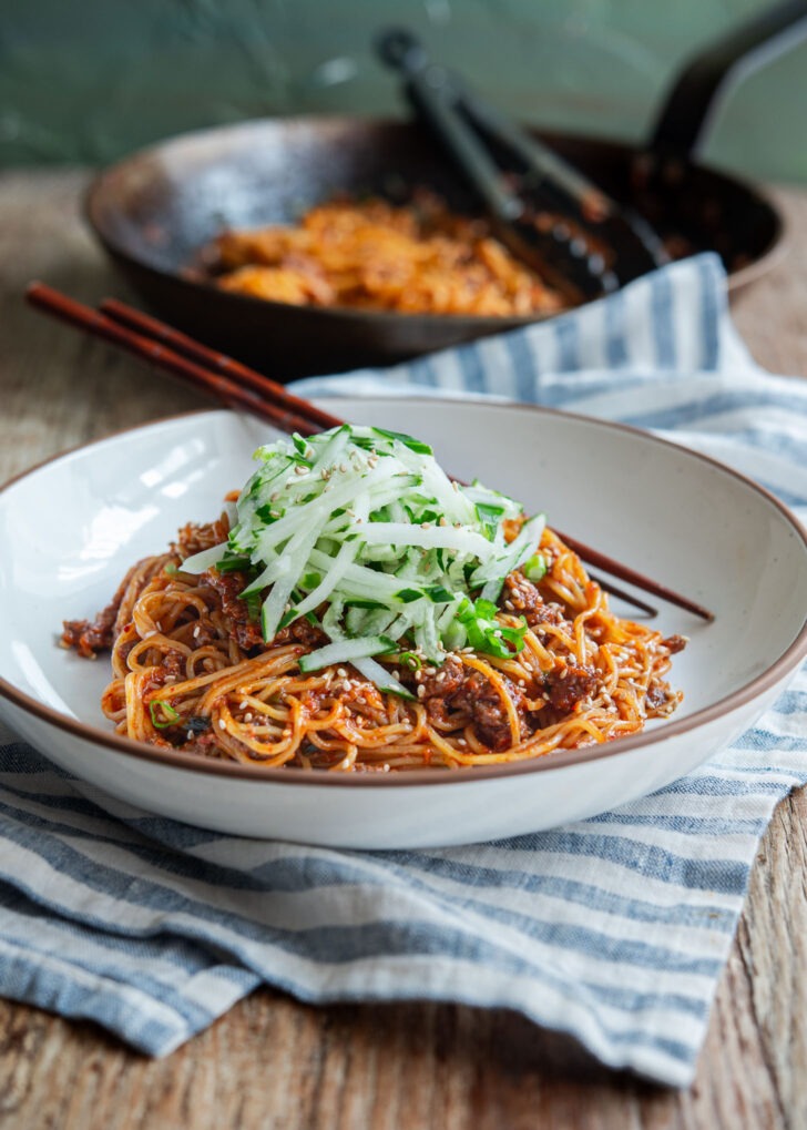 Beef gochujang noodles topped with shredded cucumber in a bowl