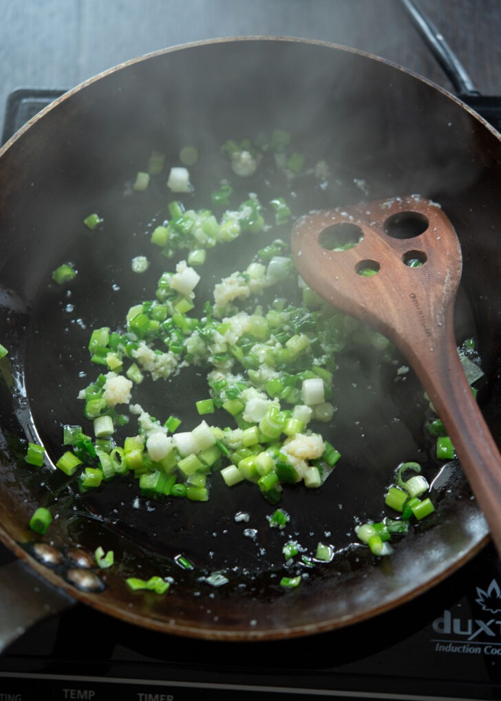 Green onion and garlic frying in a skillet.