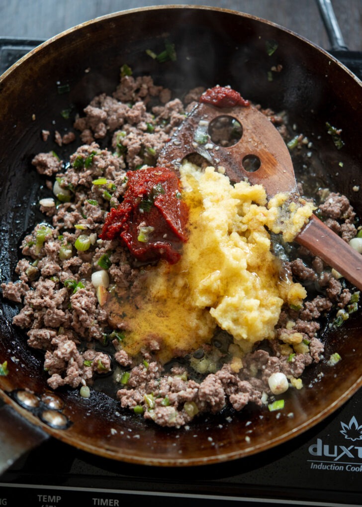 Gochujang and honey are added to ground beef mixture in a skillet