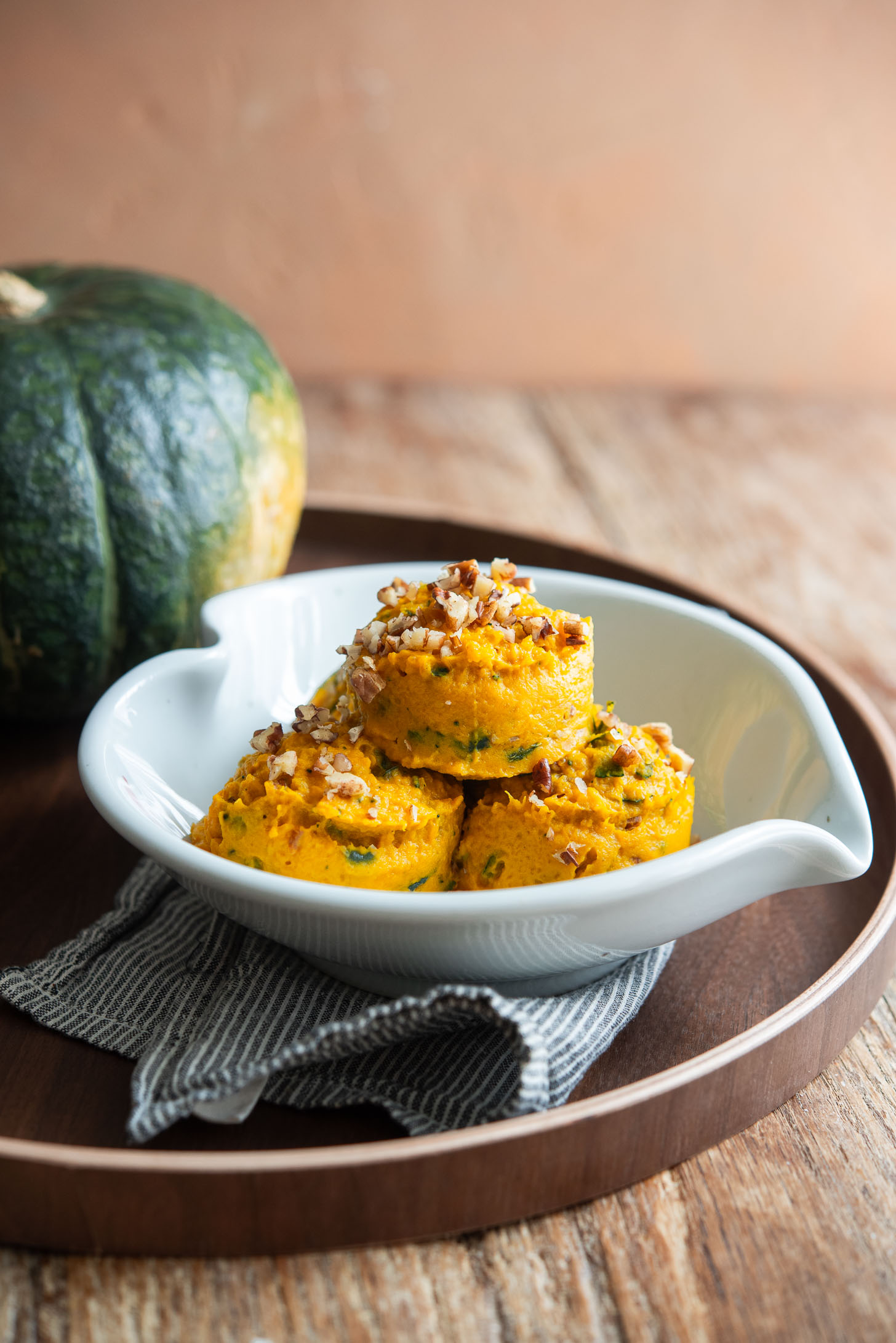Scoops of kabocha salad served in a bowl and garnished with chopped nuts on top.