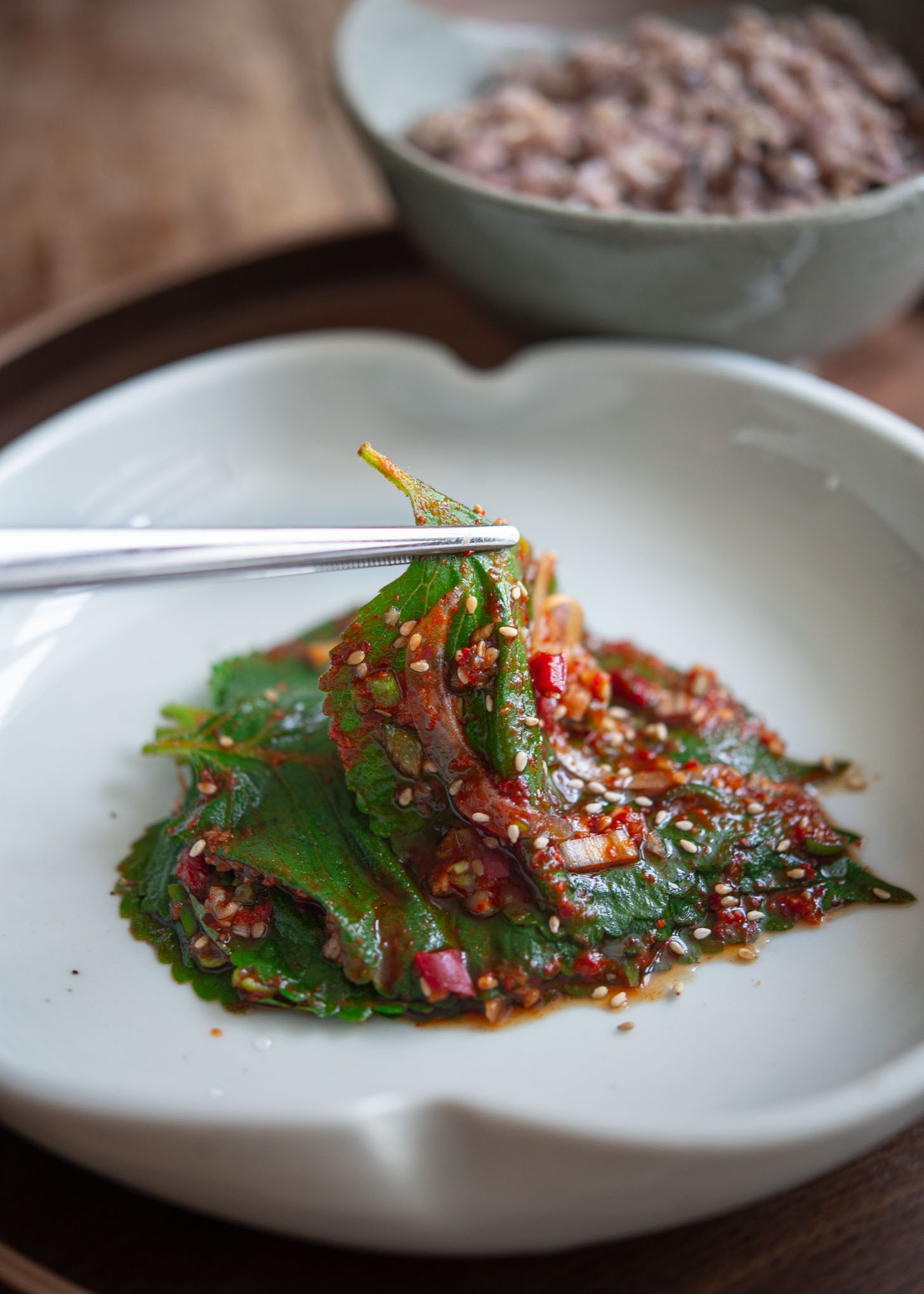 Chopstick picking up a piece of perilla leaf kimchi.