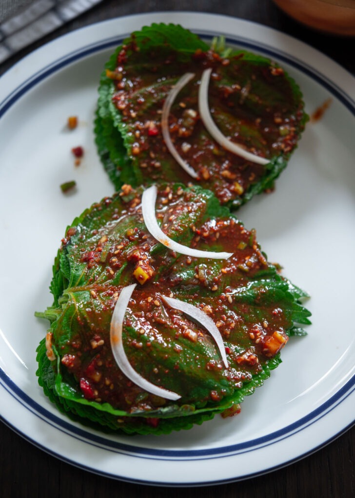 Perilla leaves coated with kimchi filling stacked together.