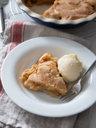 A piece of crustless apple pie served with vanilla ice cream.