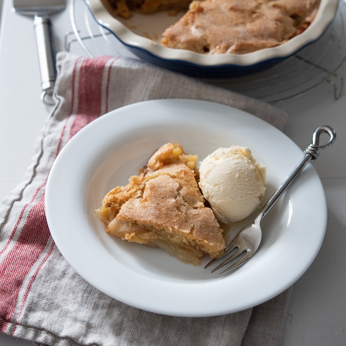 A slice of crustless apple pie is served in a bowl with a scoop of ice cream on the side.