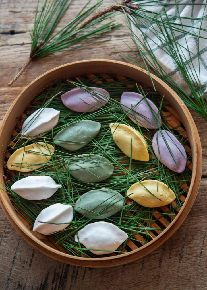 Colorful Songpyeon dough over pine needles in a bamboo basket.