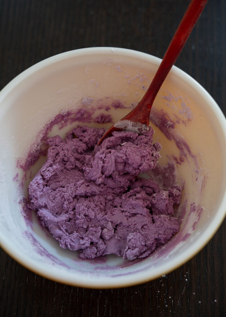 Purple songpyeon dough is mixed with a spoon.