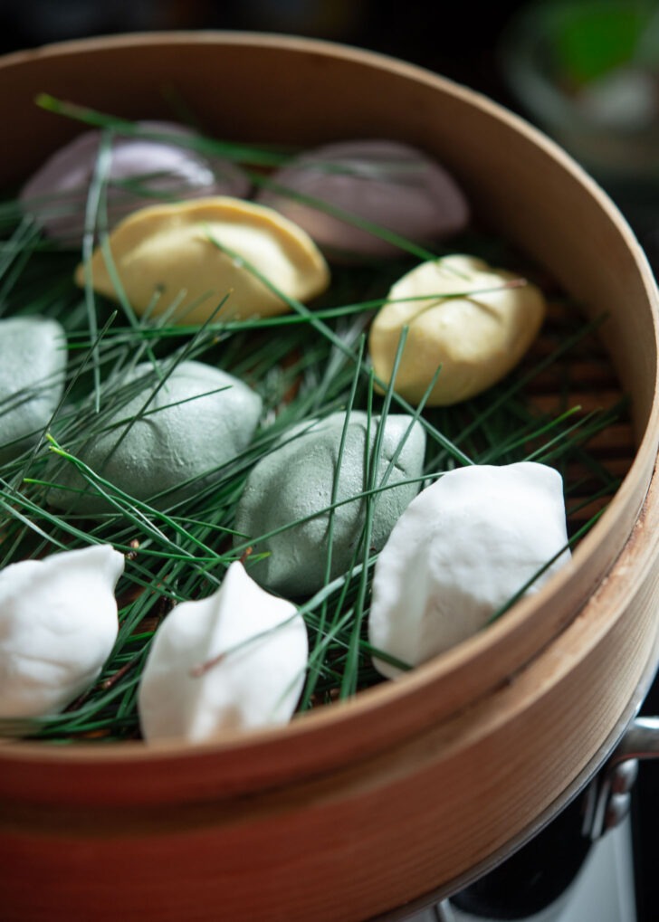Raw songpyeon are placed on the beds of pine needles in a bamboo basket.
