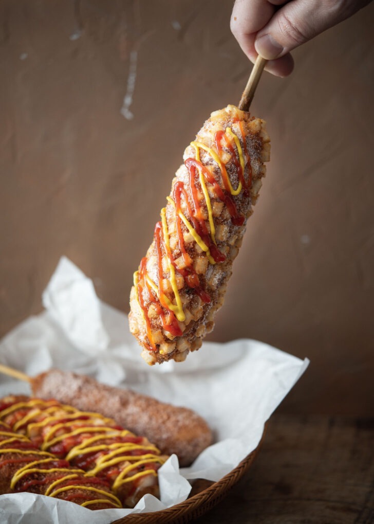 Korean potato corn dog drizzled with condiments.