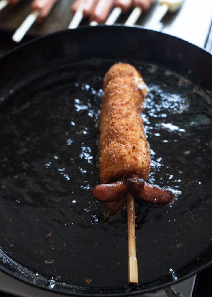 Korean hot dog with octopus leg deep frying in oil.