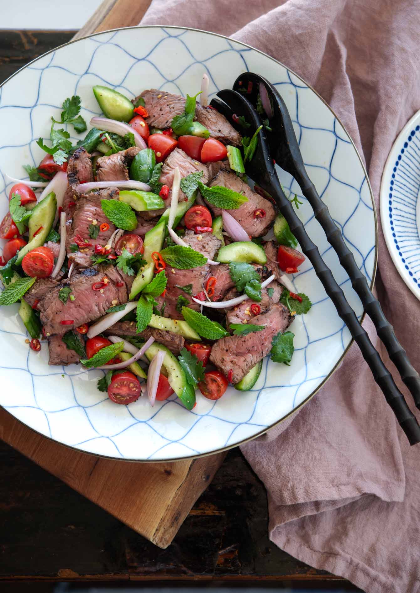 Thai beef salad garnished with fresh herbs on a serving platter. 