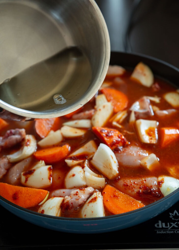 Sea kelp stock added to chicken and carrot mix in a pan.