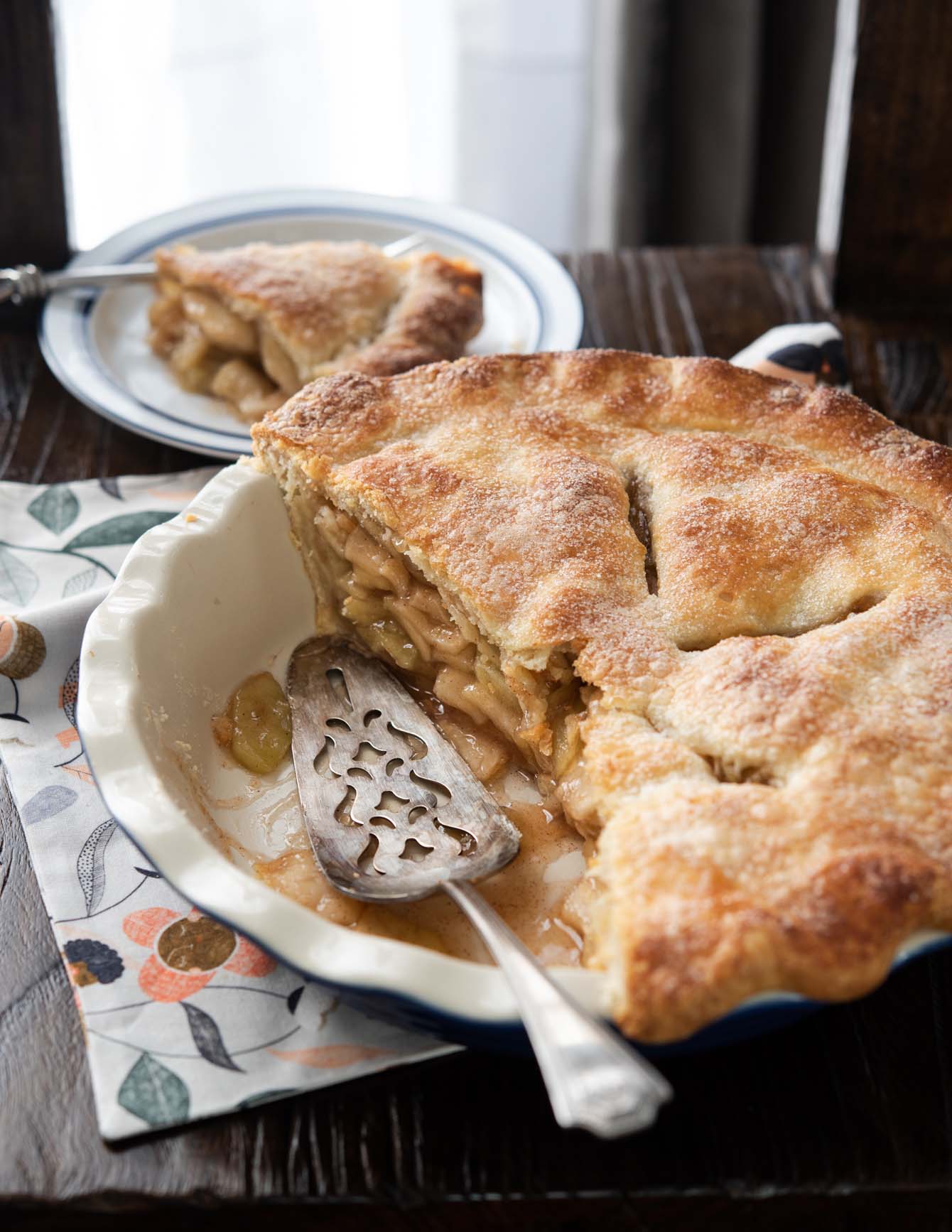 Apple pie in a deep dish pan showing the soft apple filling inside.