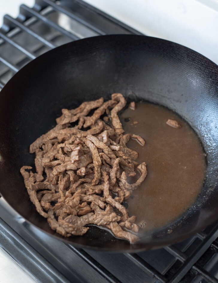 Beef strips cooked leaving meat juice in a skillet.