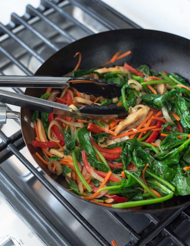 Japchae veggies stir-frying in a skillet.