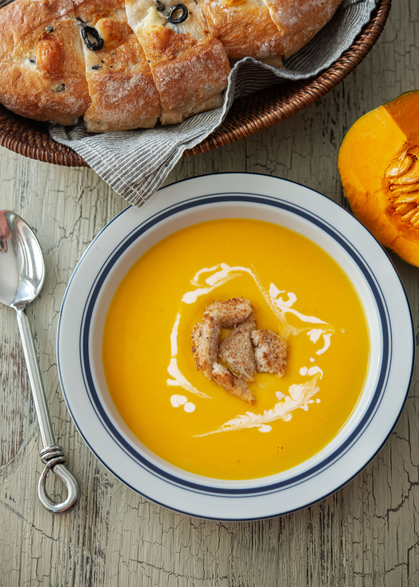 A bowl of kabocha squash soup garnished with cream and crouton.
