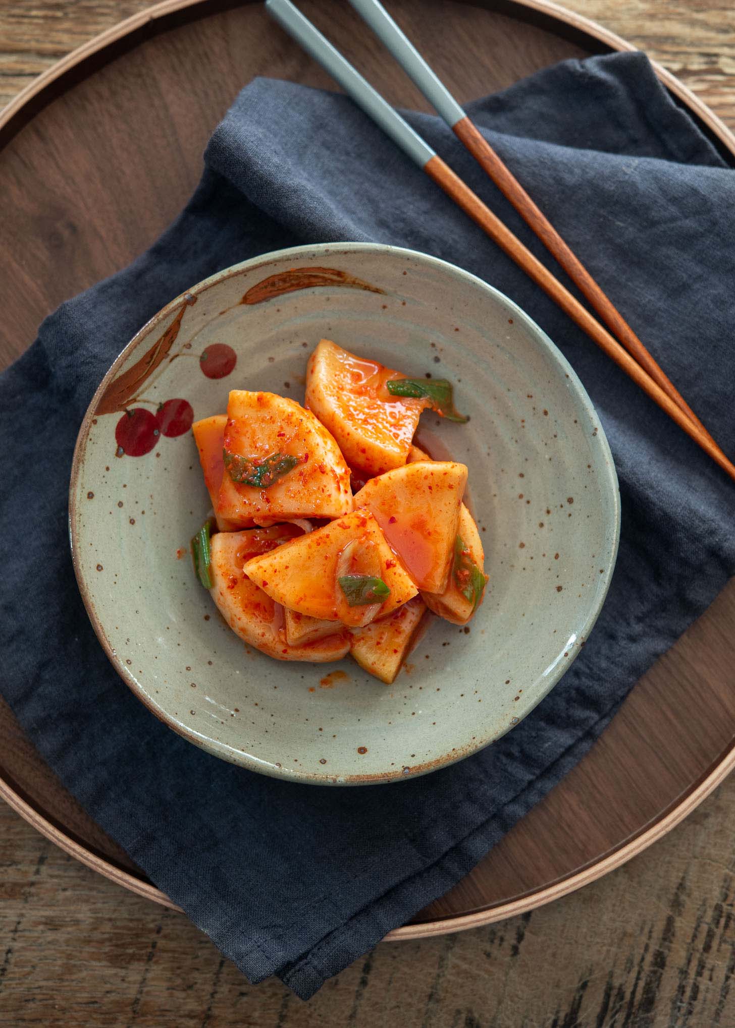 Radish kimchi (kkakdugi) in a serving dish with chopsticks on the side.