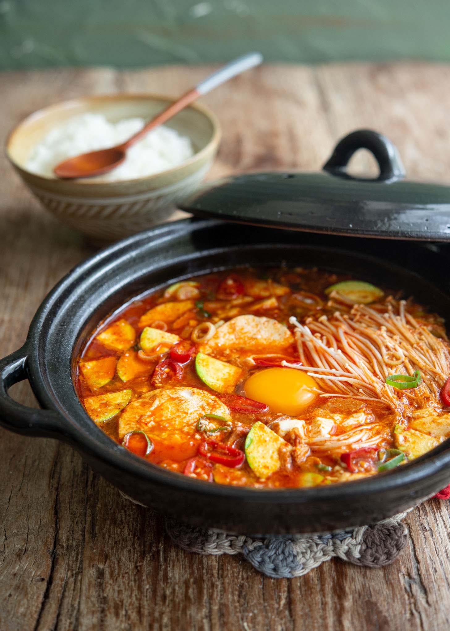 A pot of Korean tofu soup (sundubu jjigae) with rice.