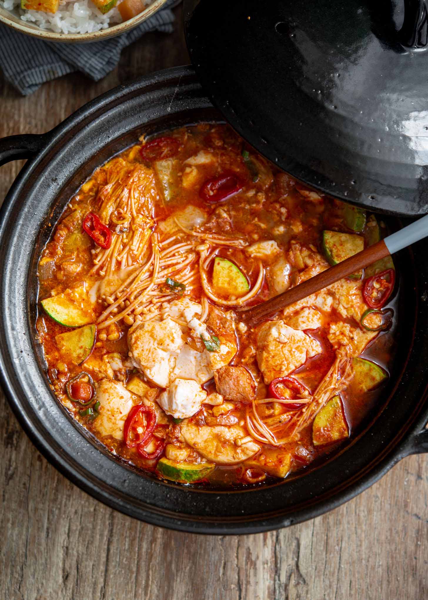 A spoonful of spicy Korean tofu soup on a pot of sundubu jjigae.