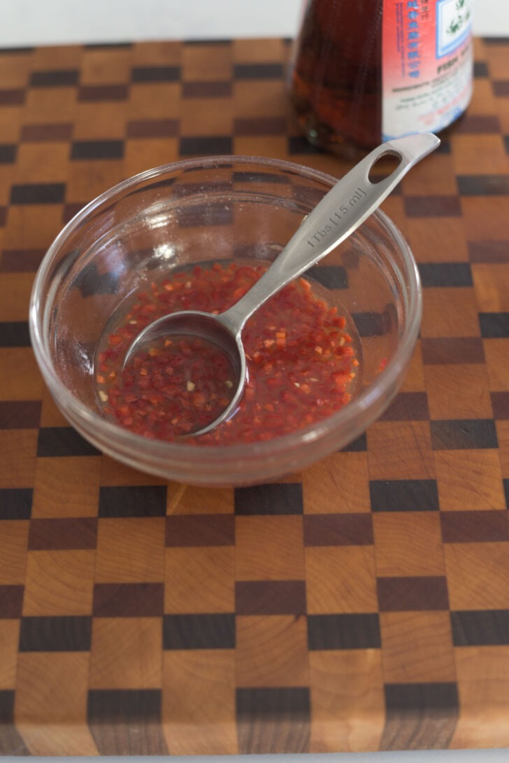 Thai salad dressing with fresh chili mixed in a small bowl.