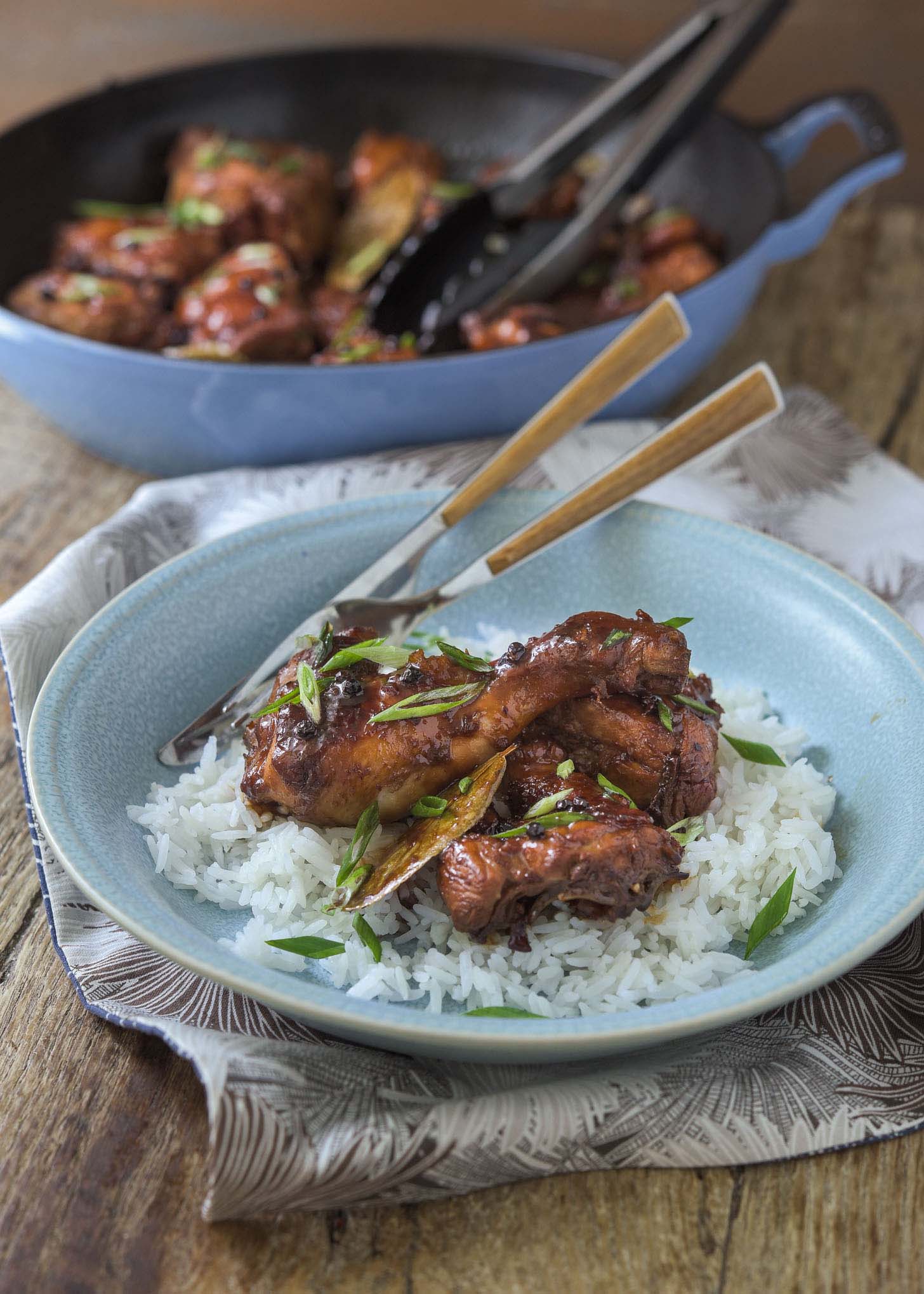 Filipino adobo chicken served over white rice in a bowl.