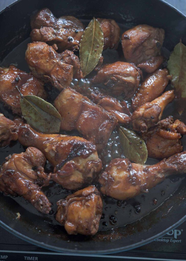 Filipino style adobo chicken glazed with sauce in a skillet.