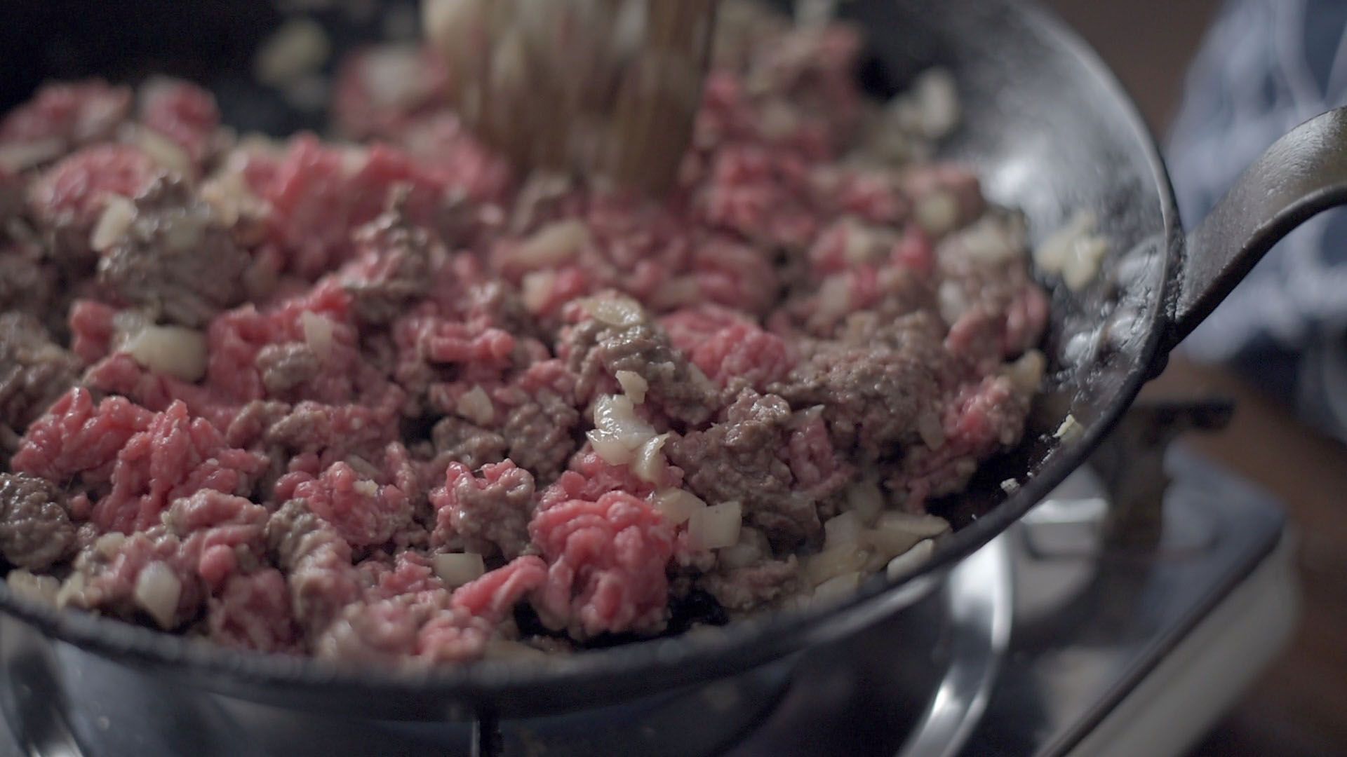 A pound of ground beef is added to the skillet to cook.