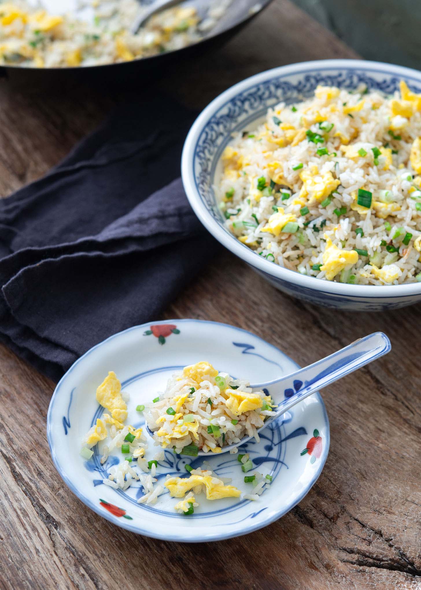 A spoonful of egg fried rice placed on a small plate.