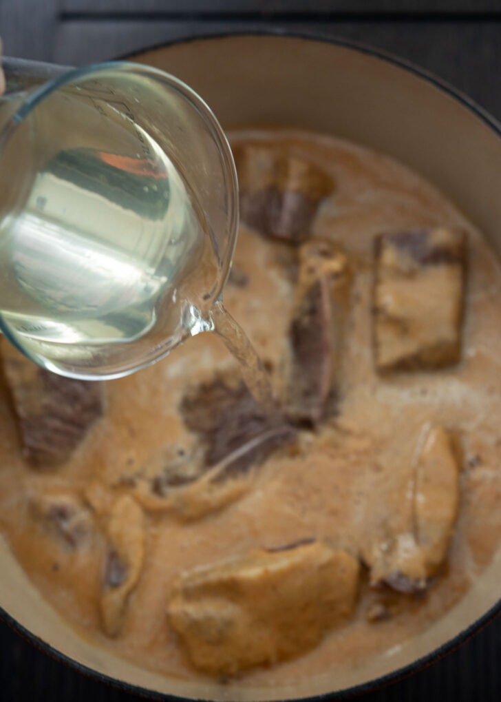 Sea kelp stock added to short ribs and sauce mixture in a pot.