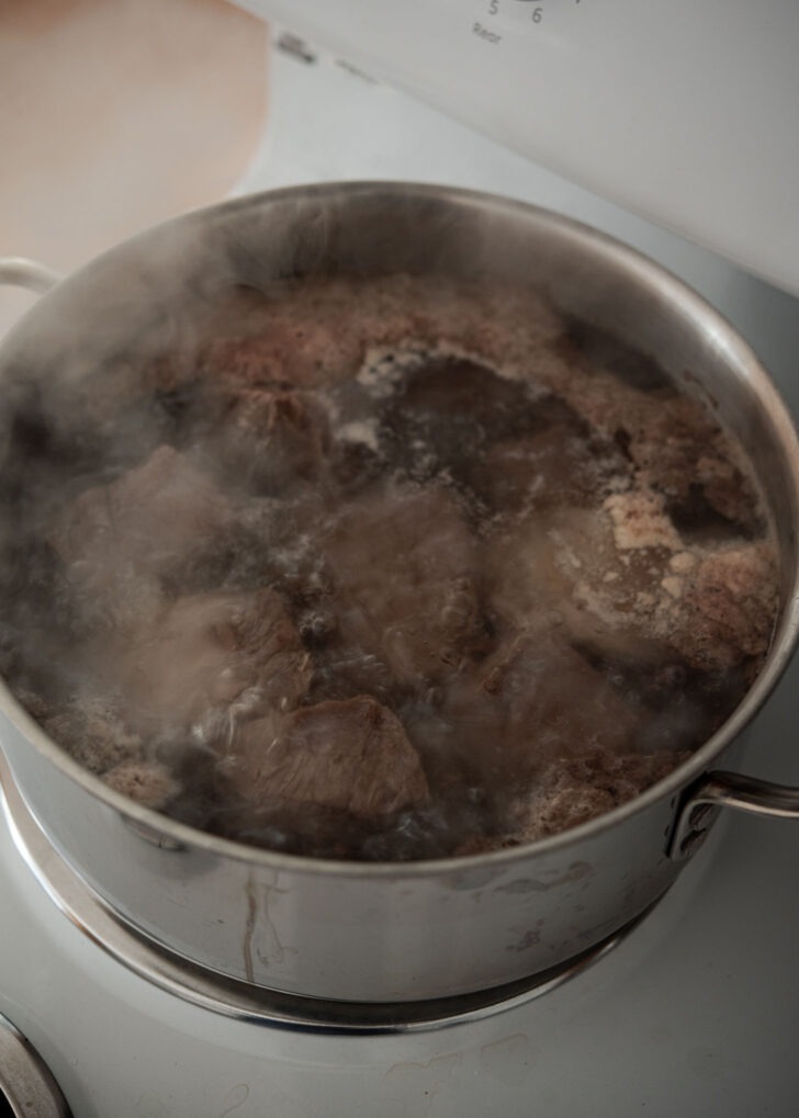 Beef short ribs parboiling in a pot of water.