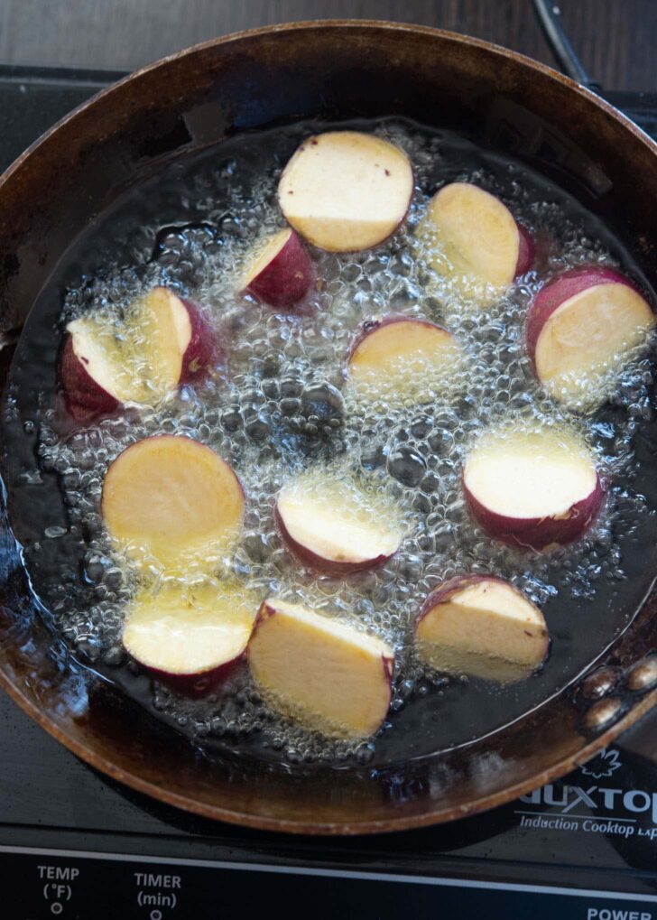 Sweet potato pieces deep frying in hot oil.