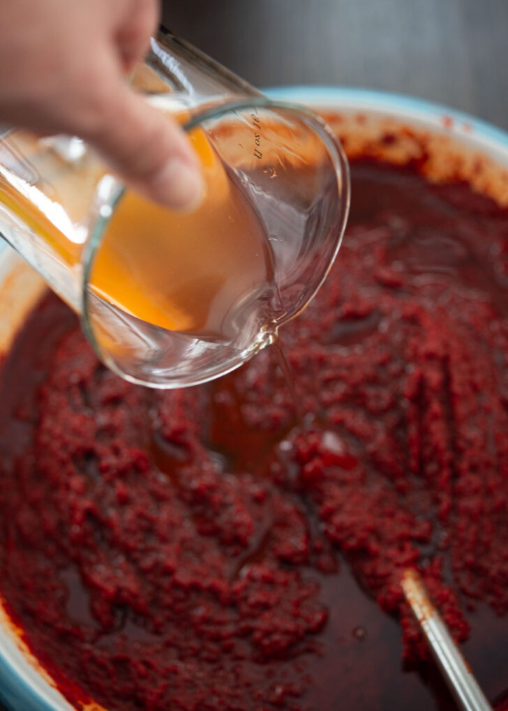 Korean plum extract added to chili paste mixture in a bowl.