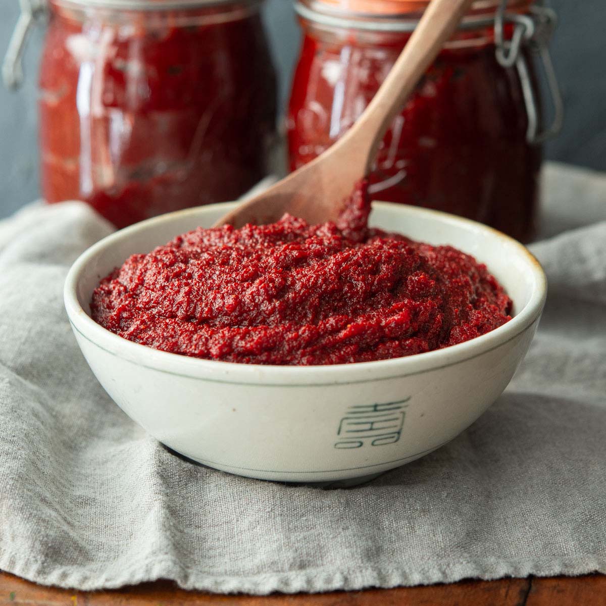 Homemade gochujang Korean red chili paste in a small ceramic bowl, showing the deep red color and thick paste texture that defines this fermented condiment