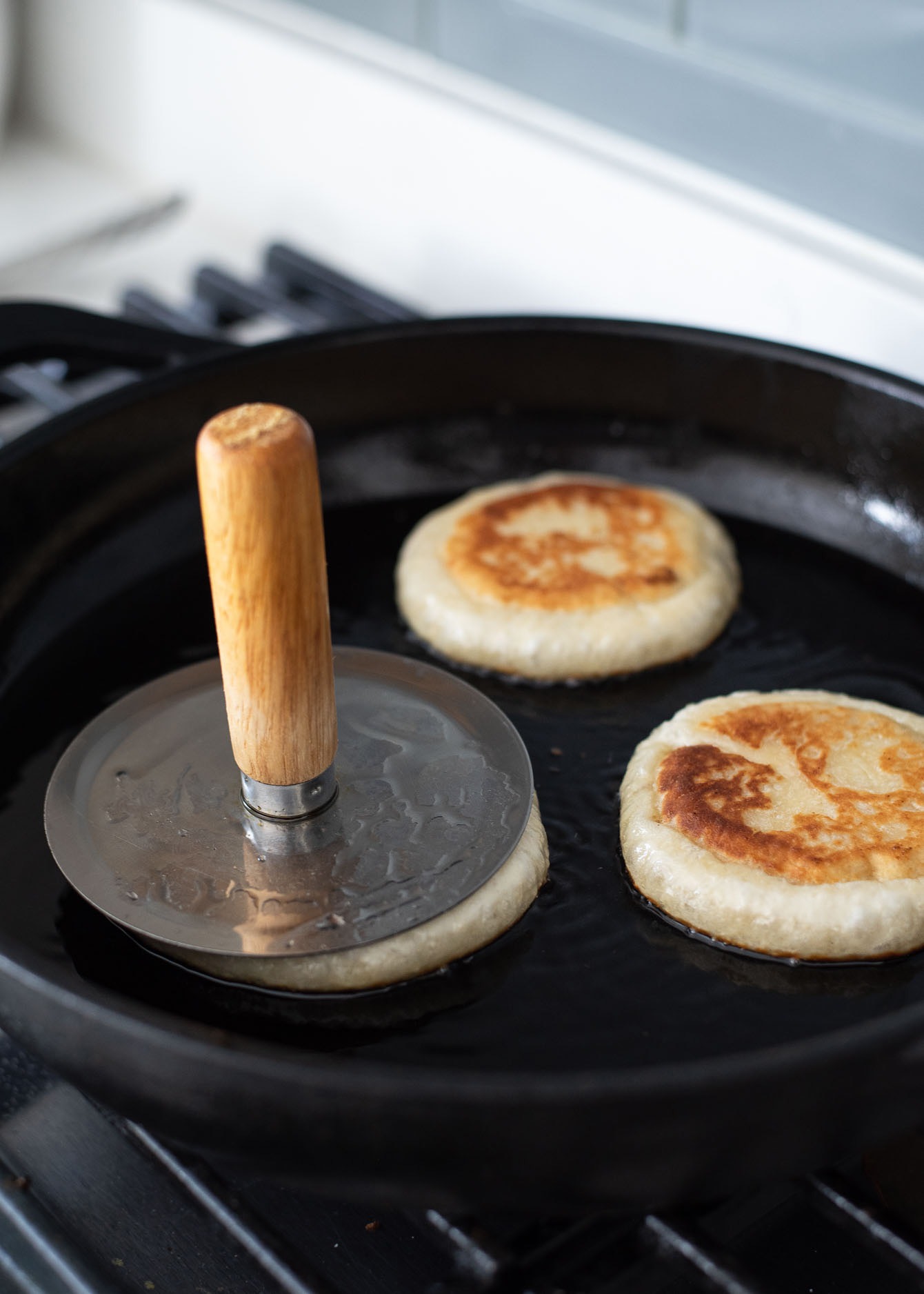 Hotteok press flattening the dough in a skillet.