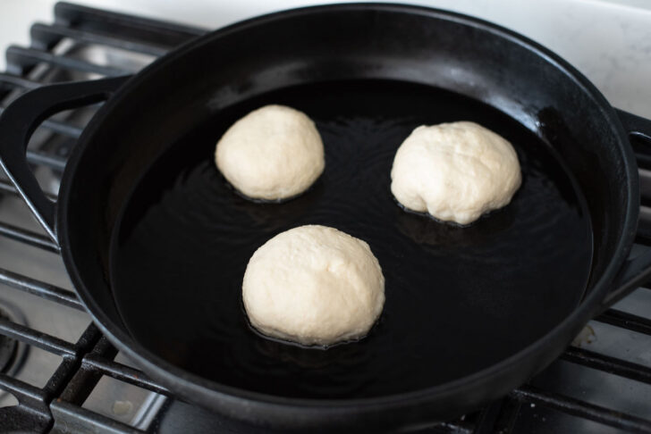 Filled hotteok dough cooking on a hot griddle.