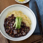 A bowl of jajangmyeon (Korean black bean noodles) garnished with cucumber.