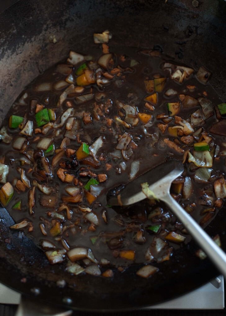 Water is added to make black bean sauce in a wok.